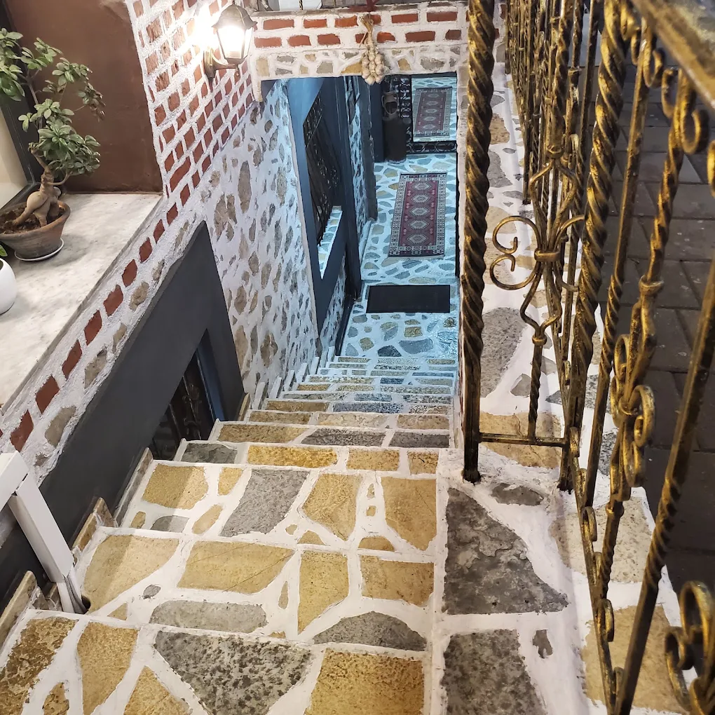 Stone steps leading down to Tradita Shqiptare, beside a wrought-iron railing.