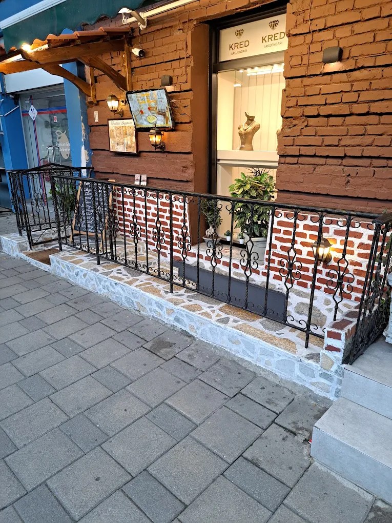 Street-side entrance to Tradita Shqiptare, with iron railings and brick walls.