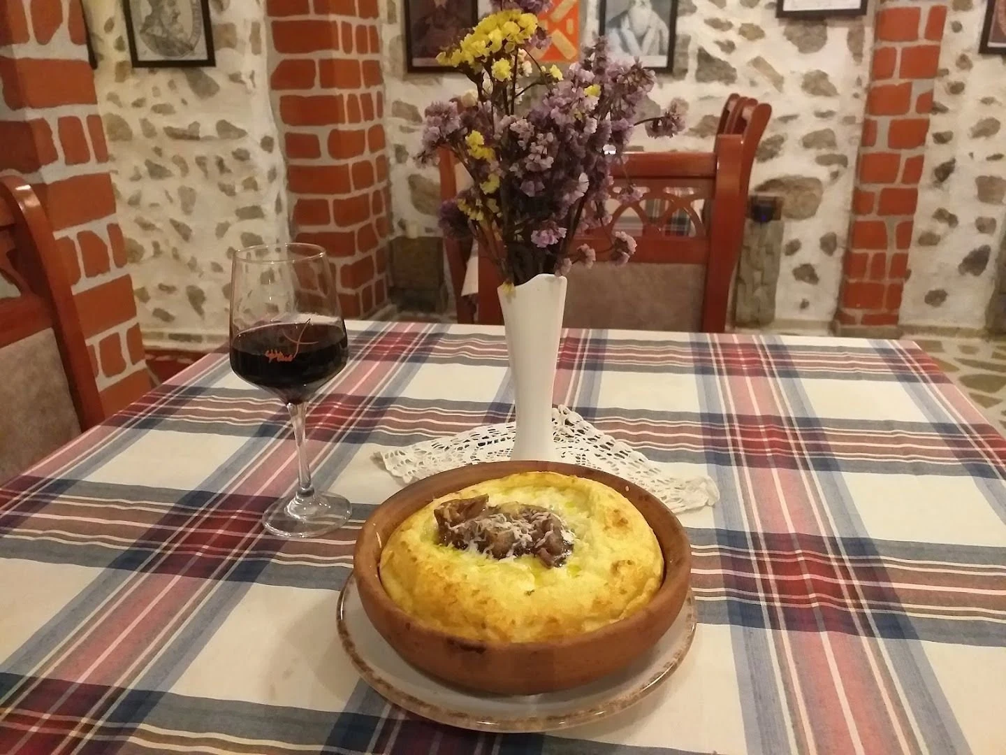 A baked dish in a clay pot on a checked tablecloth at Tradita.